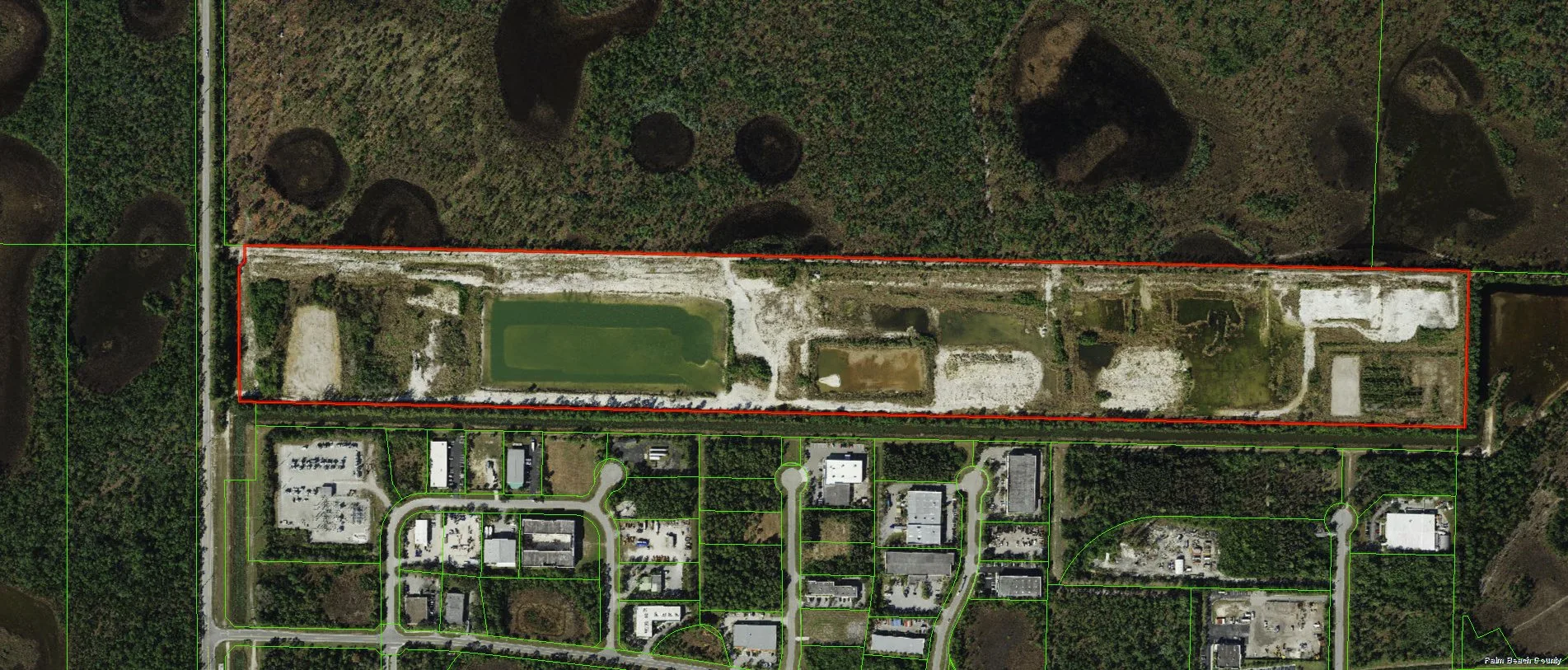 Aerial photograph of 80-acre parcel of land in South Florida proposed to be developed with surf facility (outlined in red). Green lines depict parcel boundaries. Adjoining the property to the north (top of photo) is a wetland area. This photograph was generated on 11-10-2021 on the Palm Beach County. Four free city and county systems: parcel viewer, code library and more