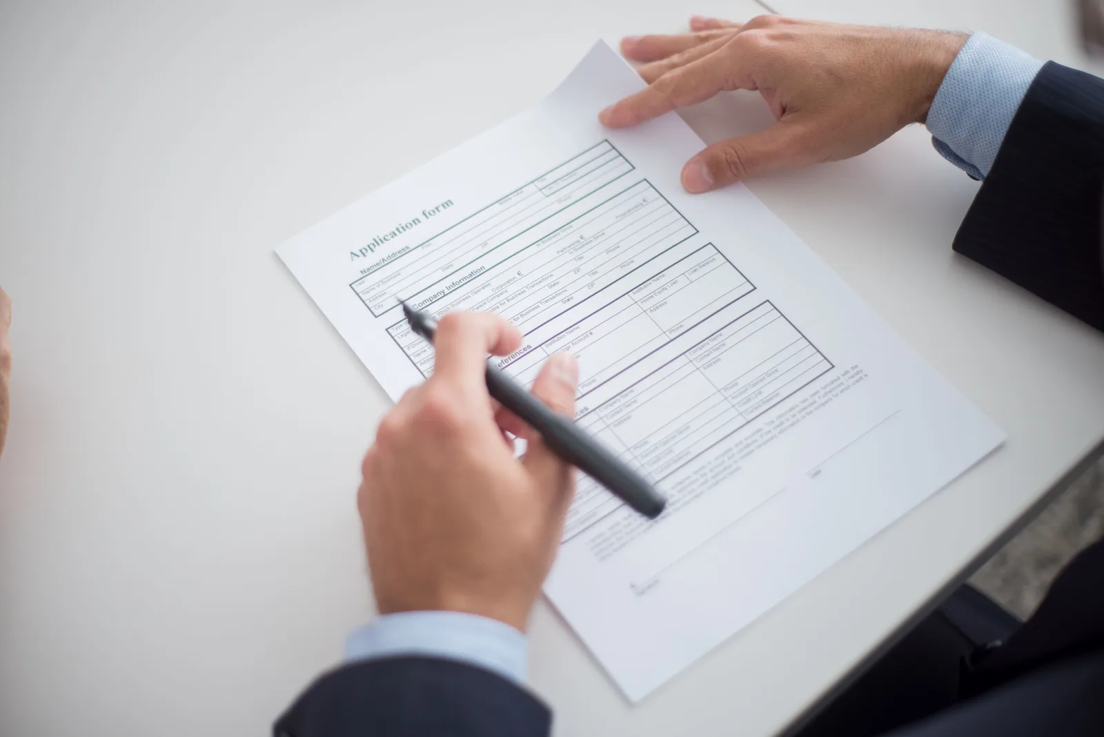 Close-up of a business professional reviewing an application form at a desk. Business License Approval: What Happens Before Opening
