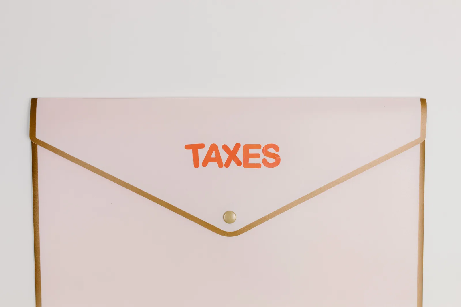 Minimalist pastel pink envelope labeled 'TAXES' perfect for finance or tax-themed visuals. 3 IRS, SBA and OSHA rules every US small business must file